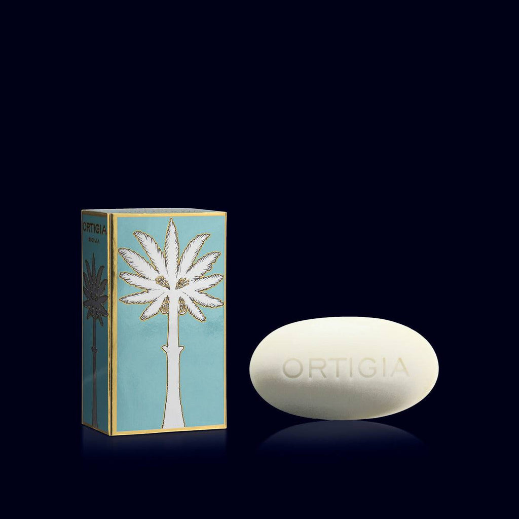 ortigia oval creamy soap next to its metallic sky blue, gold and silver gift box-florio-white flower