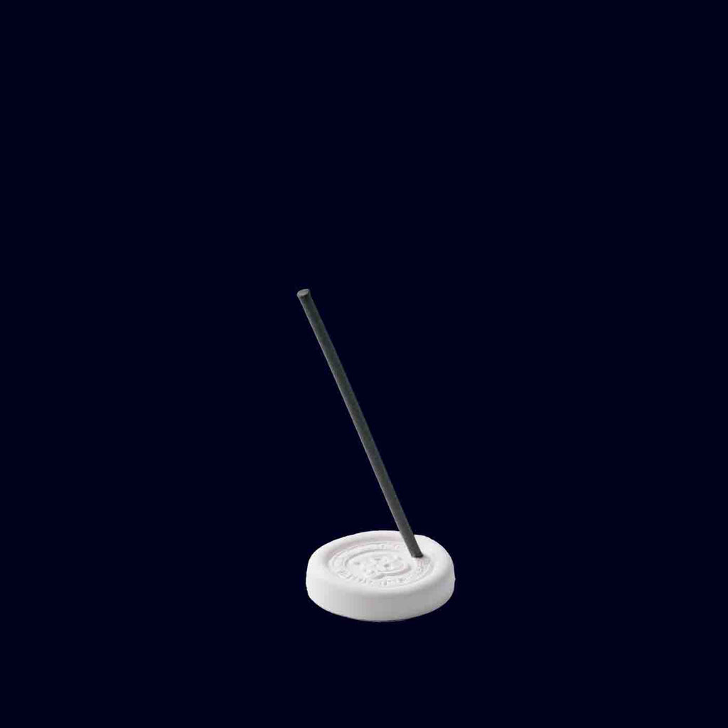 Incense stick on a white base with a black background