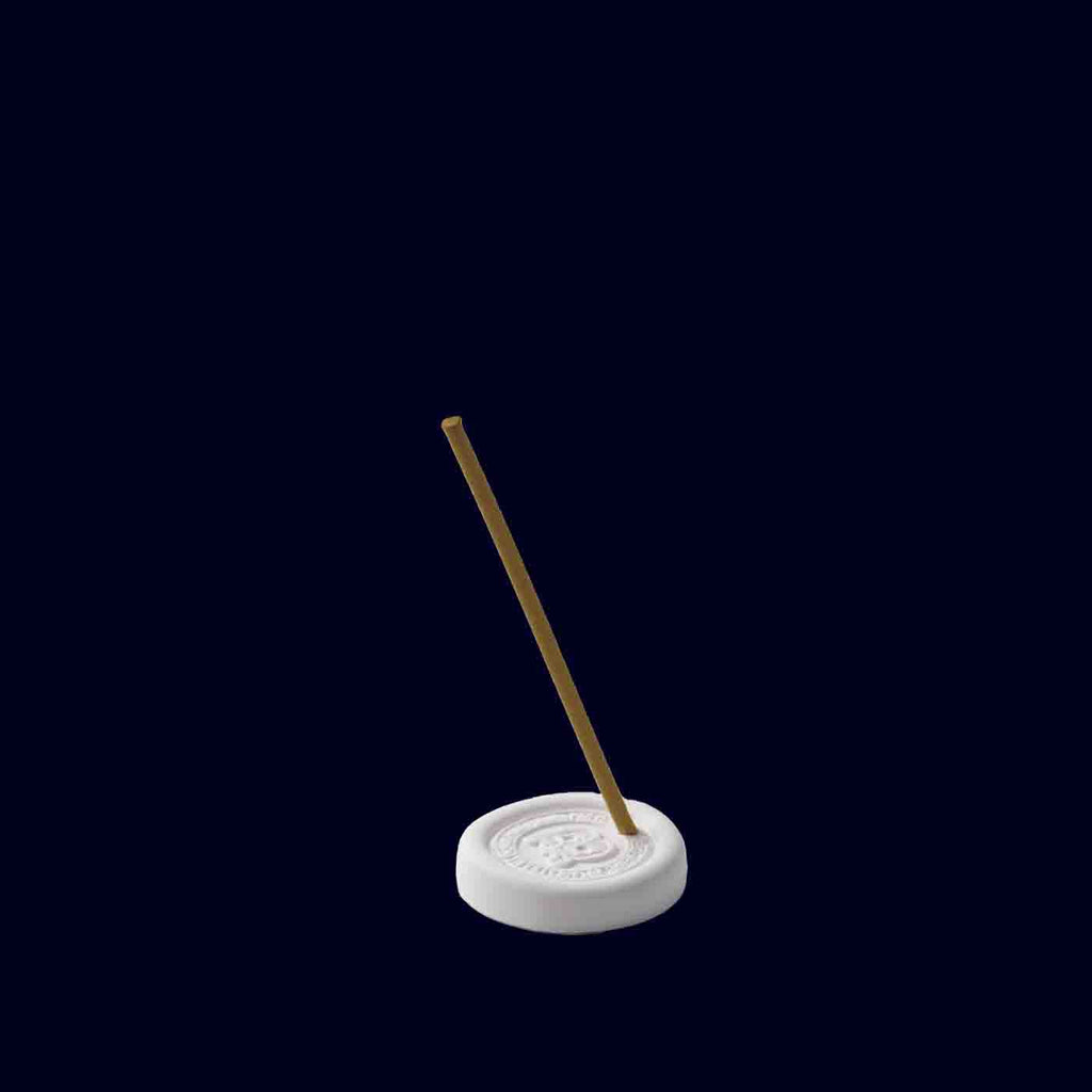 Incense stick on a white base against a black background