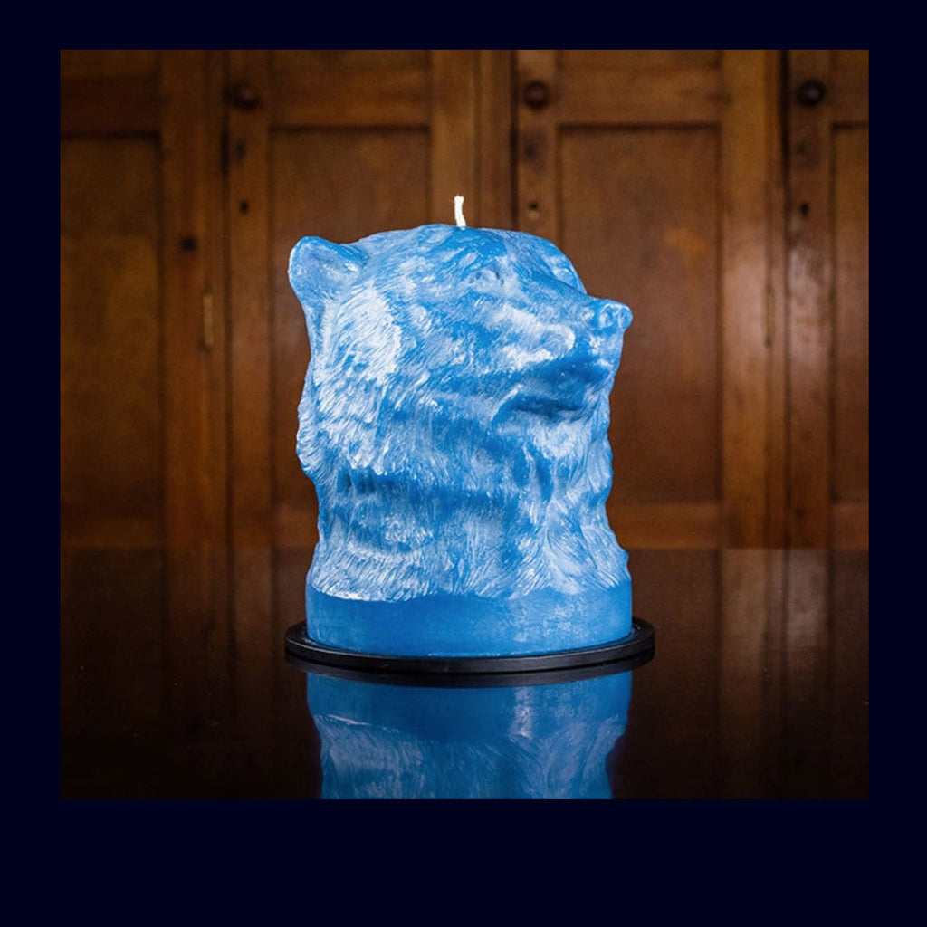 Blue bear-shaped candle on a wooden surface with a wooden panel background
