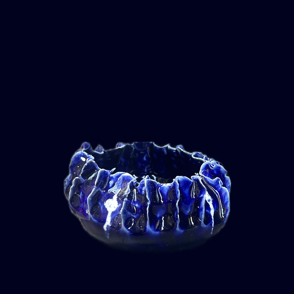 Blue ceramic bowl with textured surface on a black background