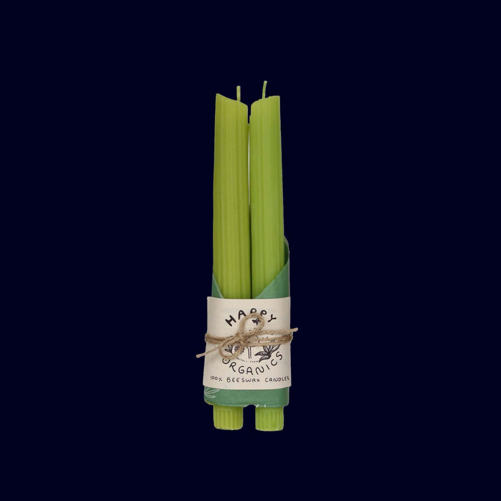Set of green candles STICK SHAPED AS CELERY STALKS wrapped with a label on a black background