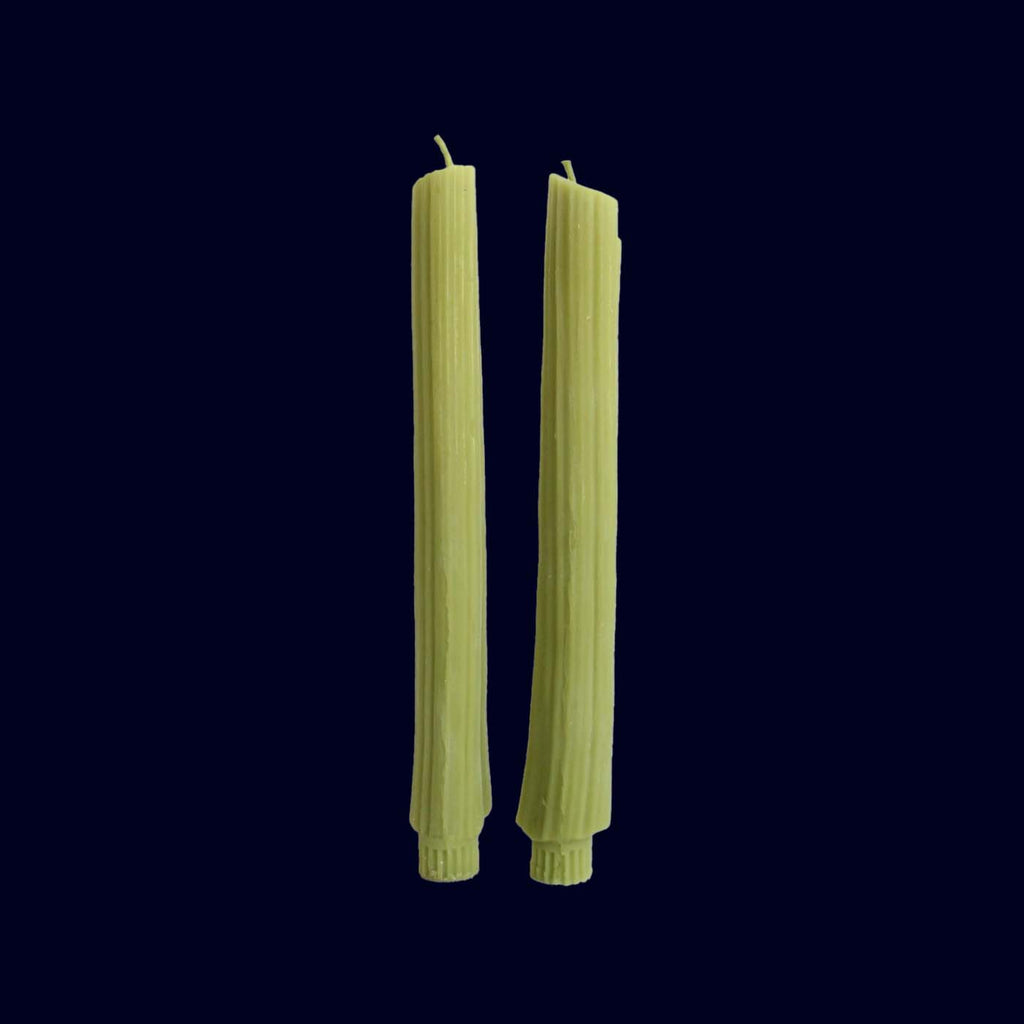 Set of green candles STICK SHAPED AS CELERY STALKS wrapped with a label on a black background