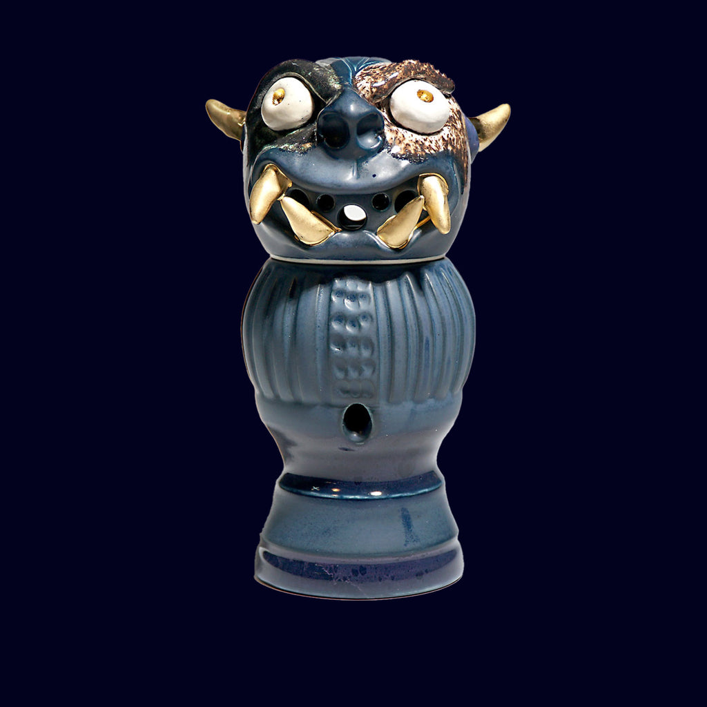 dogabi incense burner in porcelain. looks like a goblin with round eyes and gold teeth monster face top