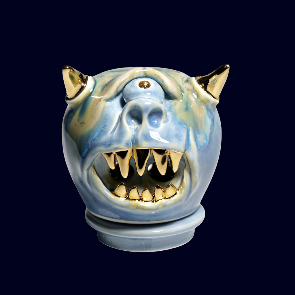 Ceramic incense burner dog head sculpture with gold accents on a black background