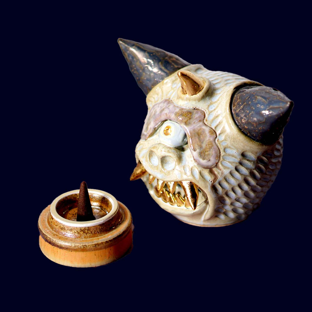 Ceramic dragon head incense burner on a dark background
