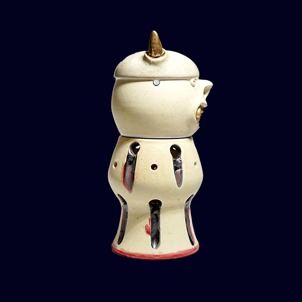 dogabi incense burner in porcelain. looks like a goblin with round eyes and gold teeth monster face top