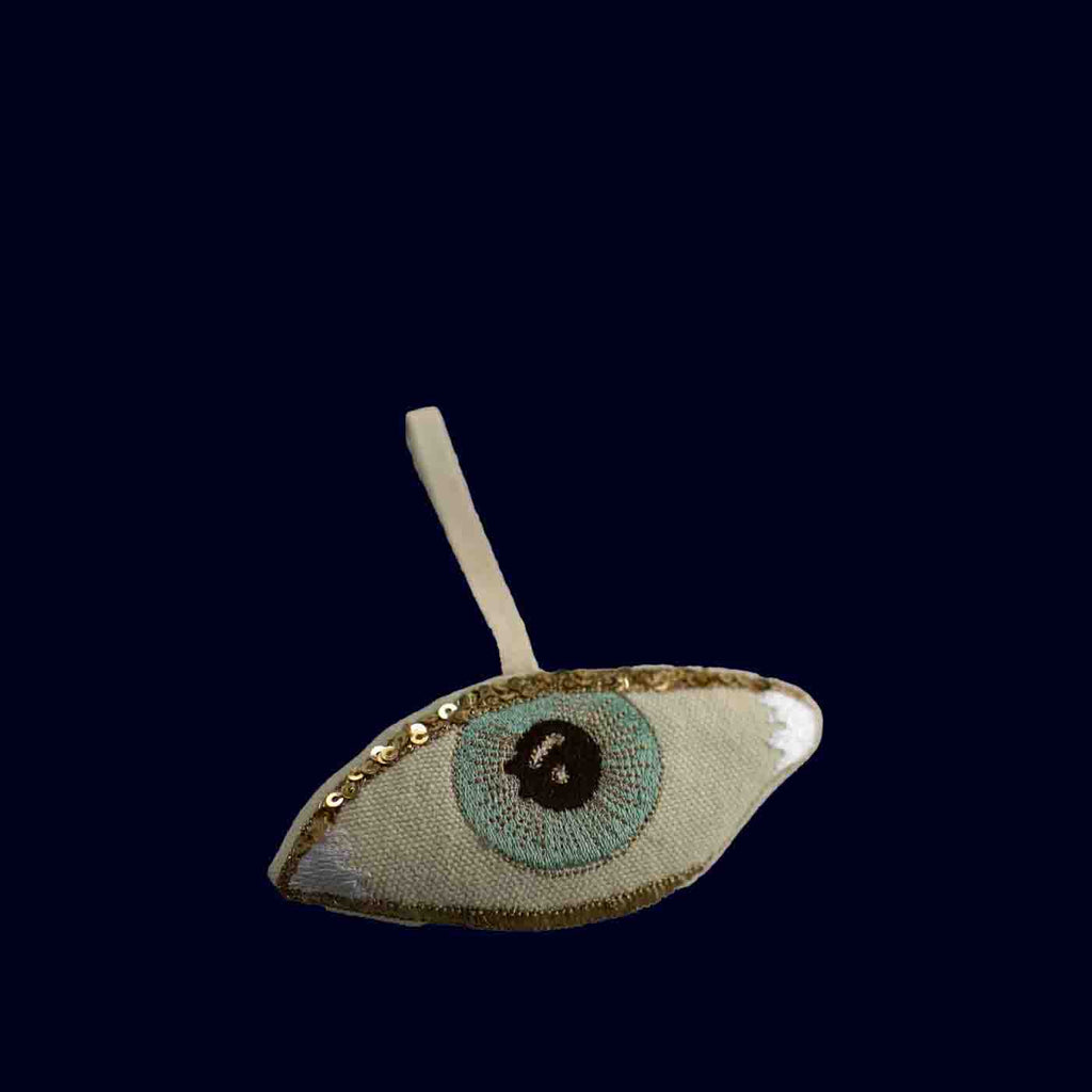 Decorative eye-shaped ornament with a black dot on a dark blue background