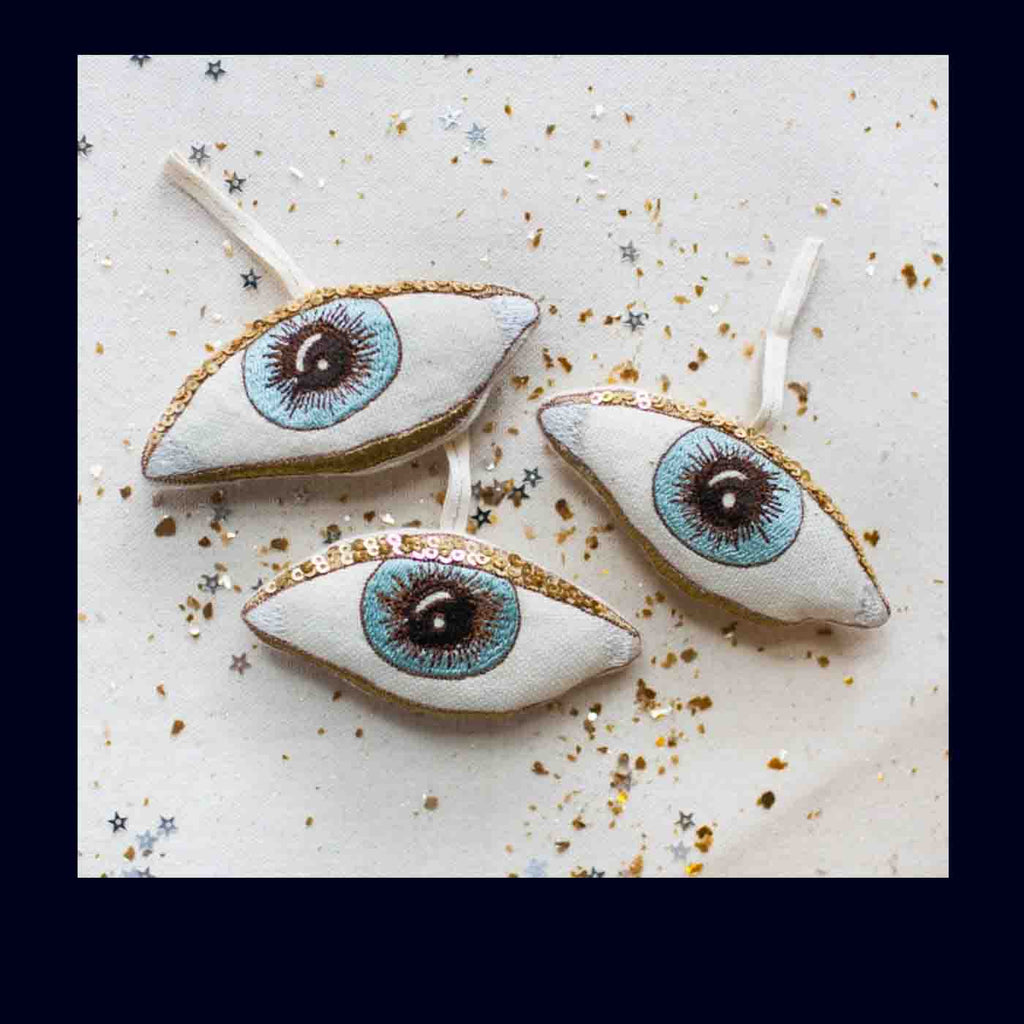 Decorative eye-shaped ornaments with blue and brown details on a textured surface.