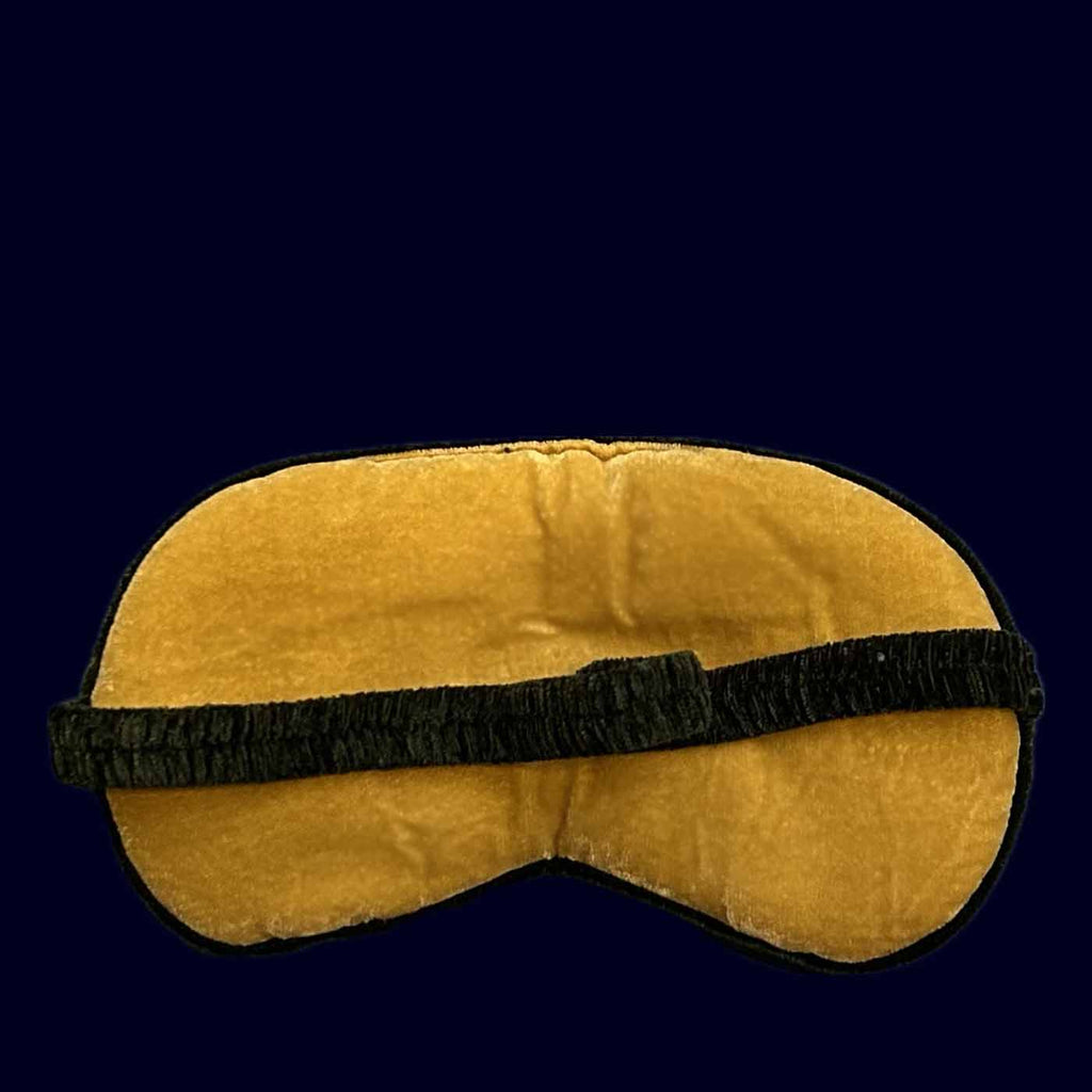 Yellow sleep mask with black strap on a dark blue background
