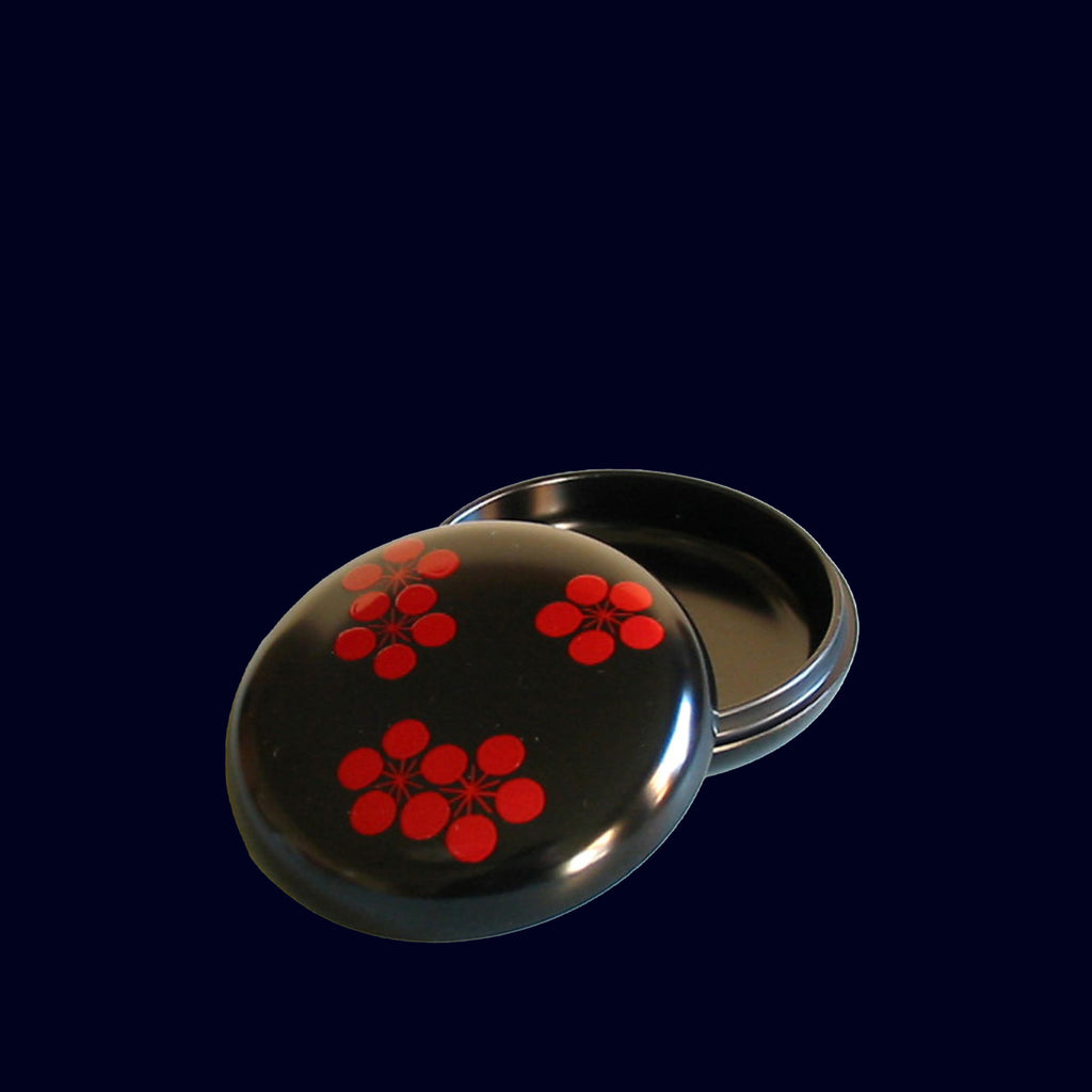 Black round container with red floral patterns on a black background