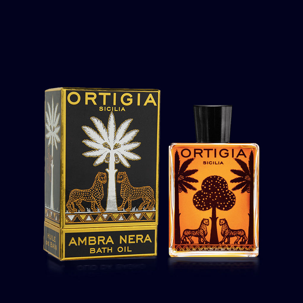 ortigia ambra nera bath oil in a glass bottles printed with black palm trees and leopards with its black and silver box