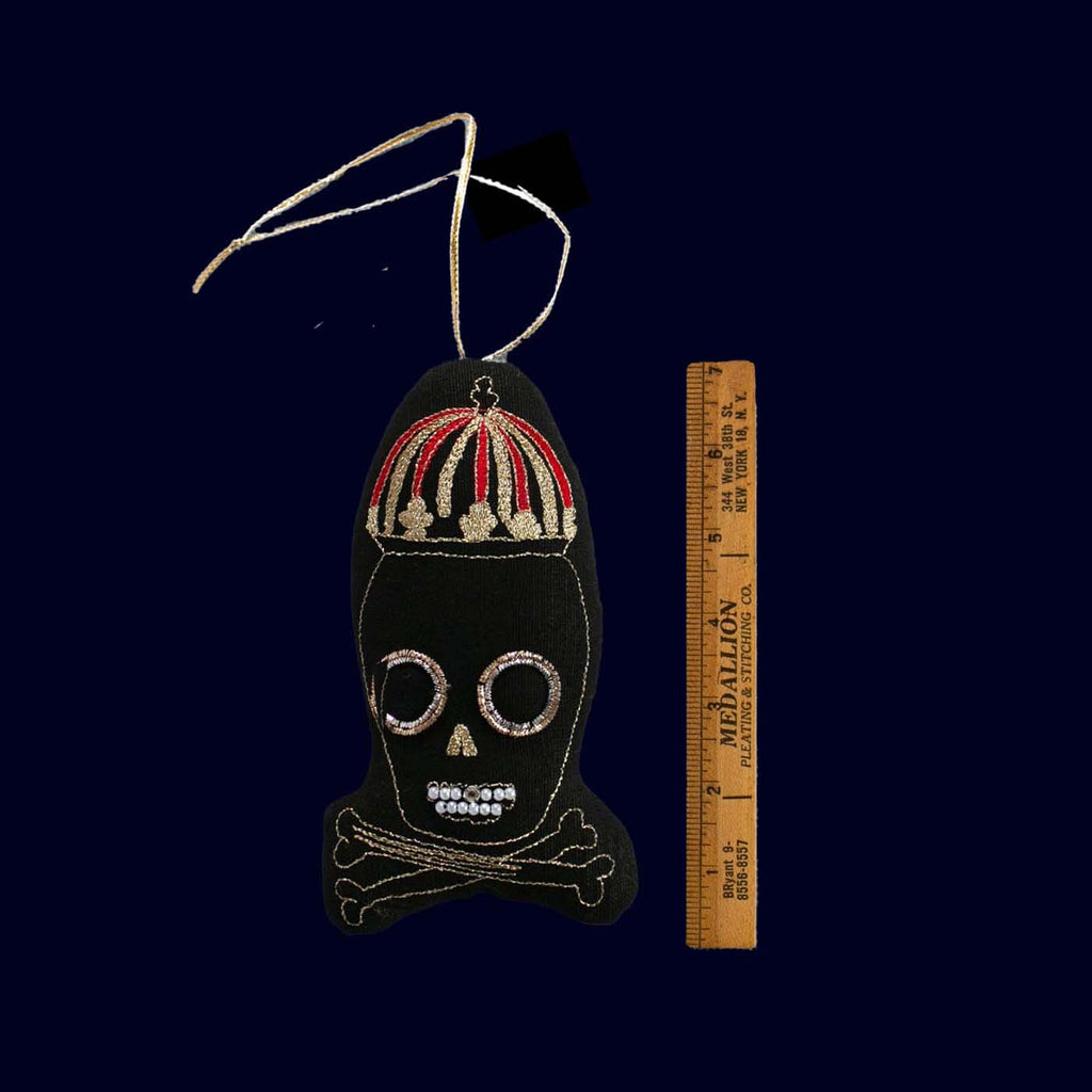 Decorative skull ornament with a ruler for scale on a dark background