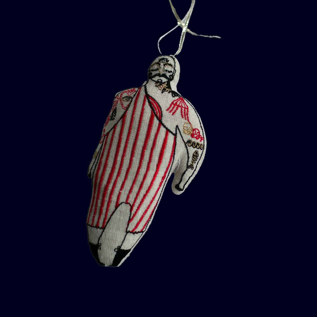 Decorative ornament shaped like a person in a red and white striped outfit on a dark background