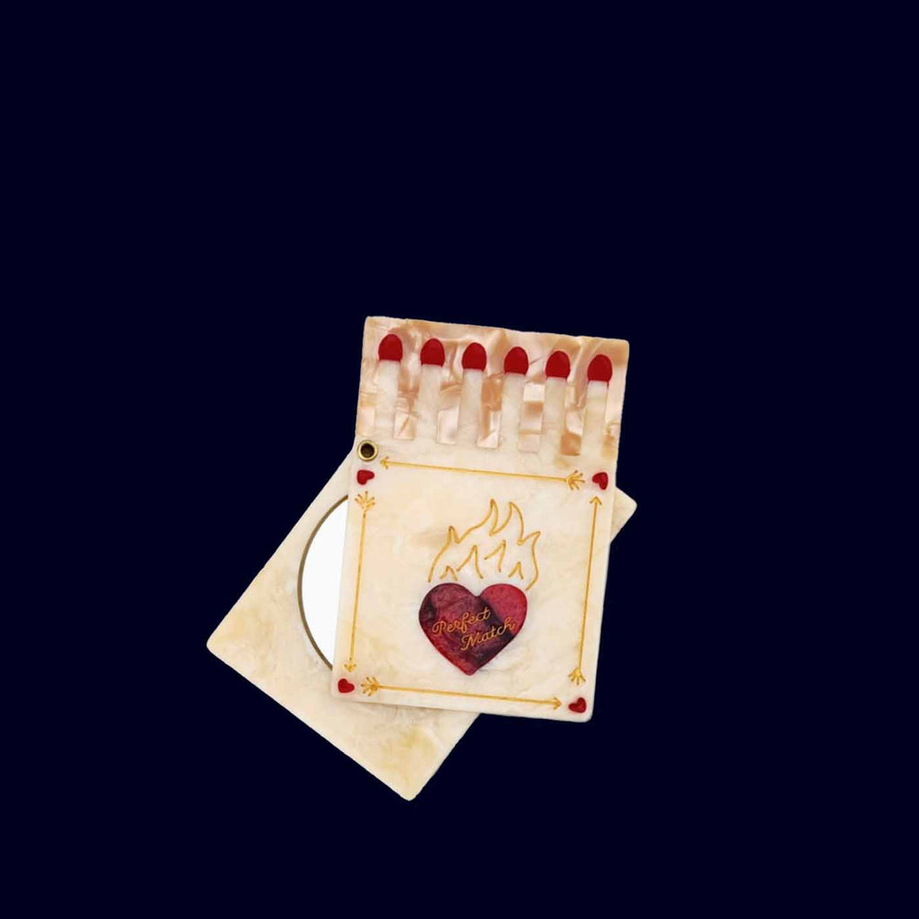 Small hand mirror with a heart design on a dark background